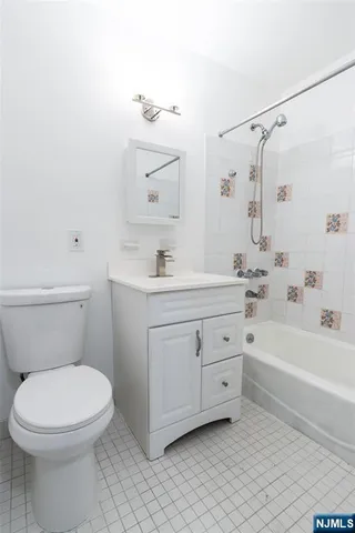 a bathroom with a toilet a sink a mirror a bathtub and vanity