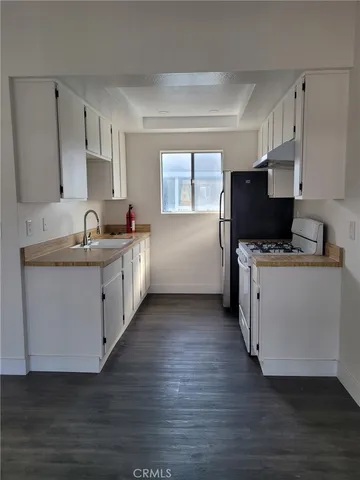 a kitchen with granite countertop a sink wooden floor and white appliances