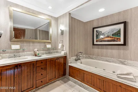 a bathroom with a tub double sink and mirror
