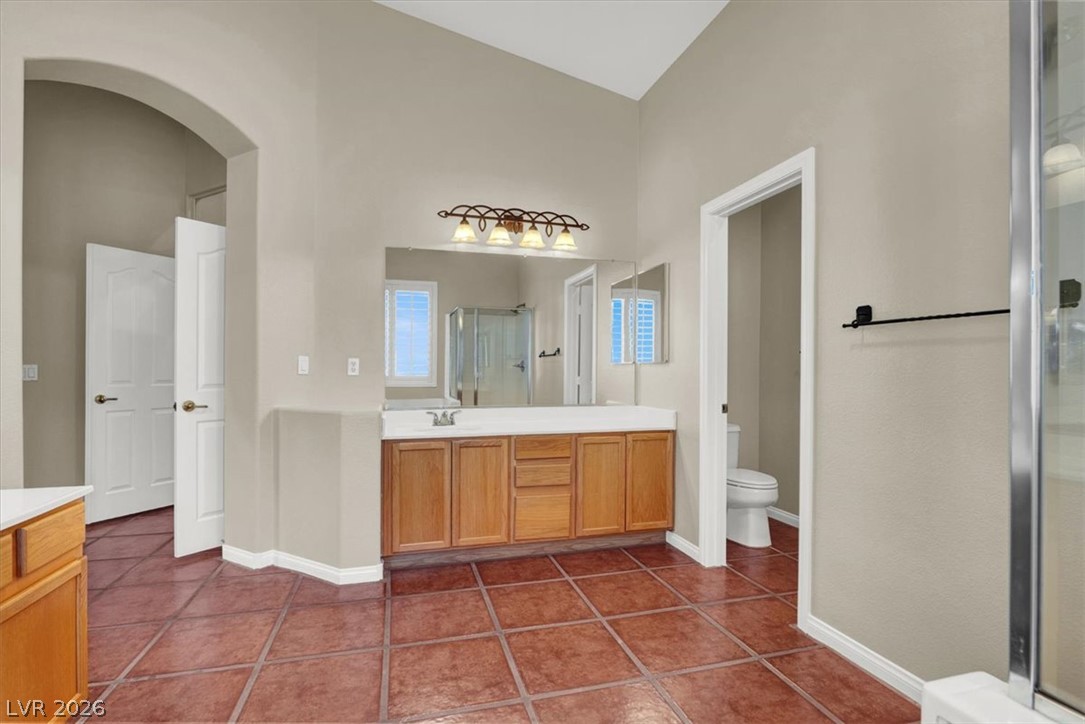7308 Rustic Meadow Street Las Vegas, NV 89131 - Photo 20 of 27 A spacious bathroom features vaulted ceilings, tile flooring, and a large vanity with dual sinks.