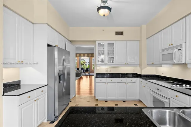 a kitchen with granite countertop white cabinets and stainless steel appliances