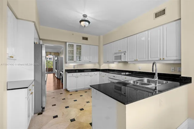 a kitchen with granite countertop a sink a stove a refrigerator and cabinets