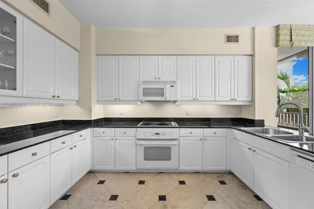 a kitchen with granite countertop white cabinets white appliances and sink