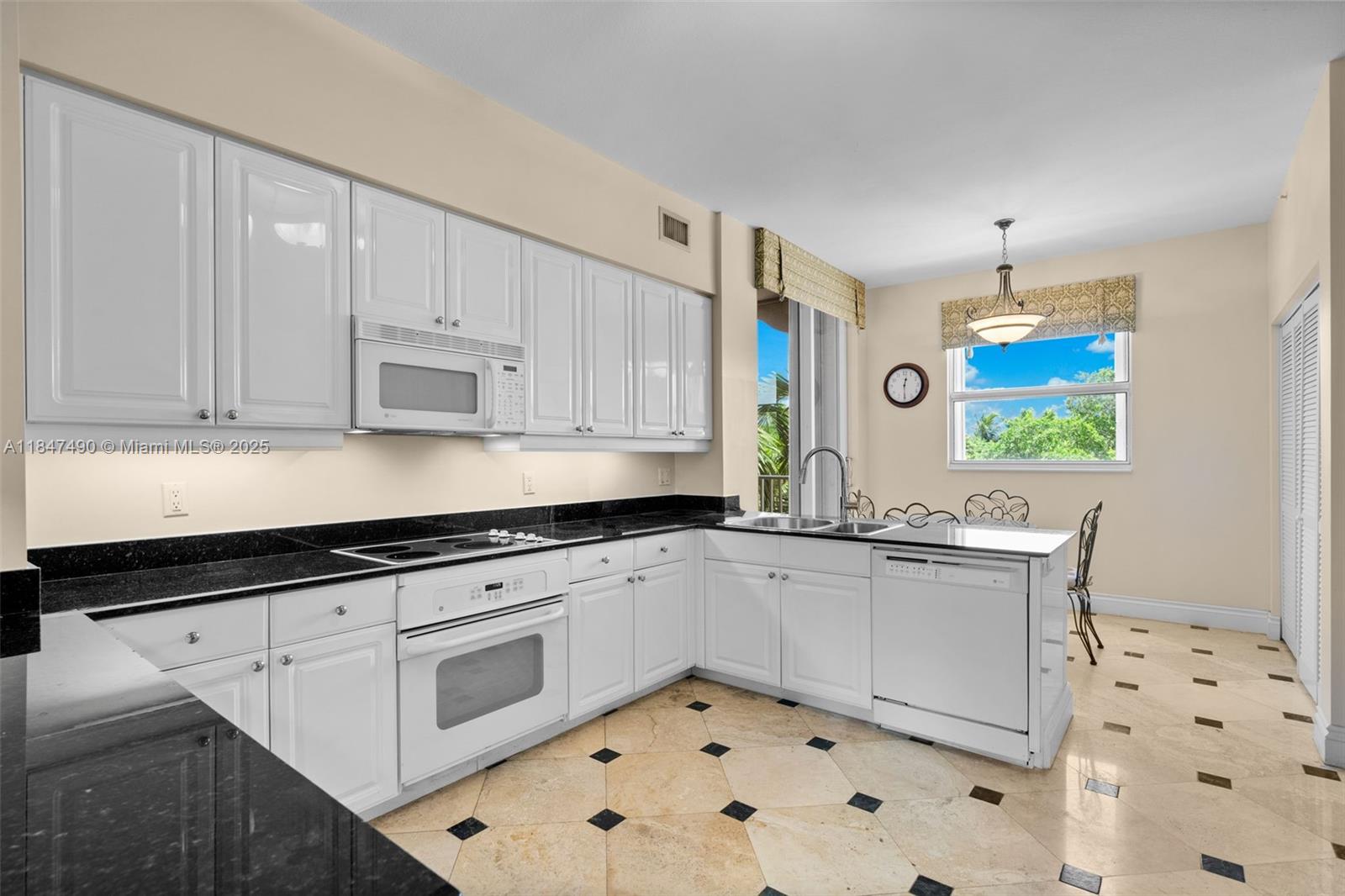 733 Crandon Boulevard, Unit 405 Key Biscayne, FL 33149 - Photo 24 of 42 a kitchen with granite countertop white cabinets and white appliances