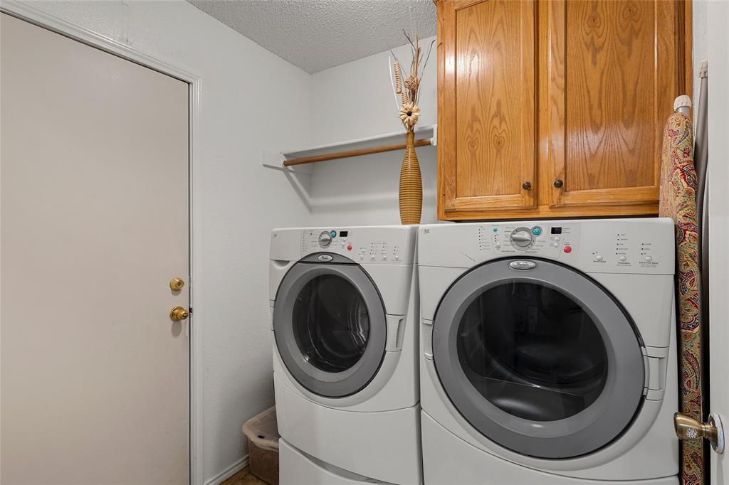 4617 Lexington Street Waco, TX 76705 - Photo 8 of 14 Dedicated laundry area featuring a white door with brass hardware, wood-finish wall cabinets, and an overhead storage shelf