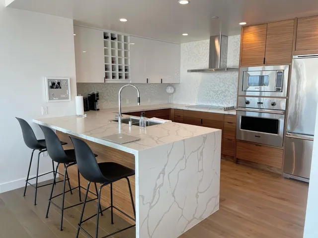 a kitchen with stainless steel appliances a sink a stove a refrigerator cabinets and dining table