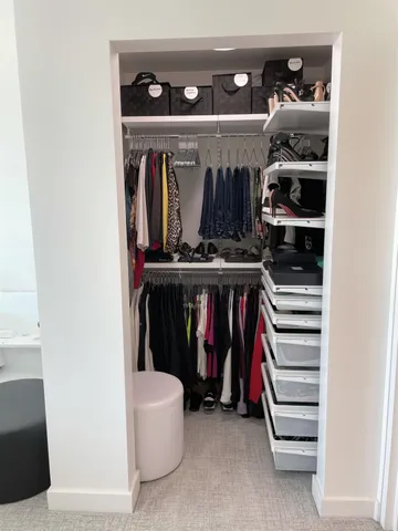 a view of walk in closet with clothes and shoes