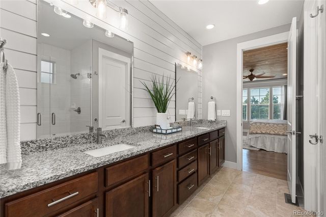 a bathroom with a granite countertop double vanity sink and a mirror