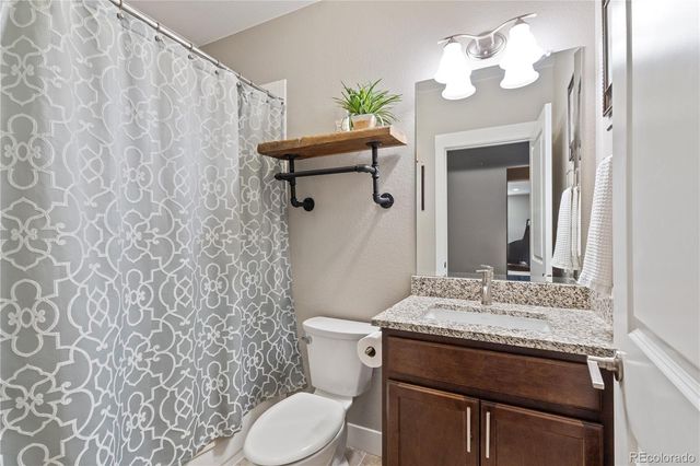 a bathroom with a granite countertop sink toilet and mirror