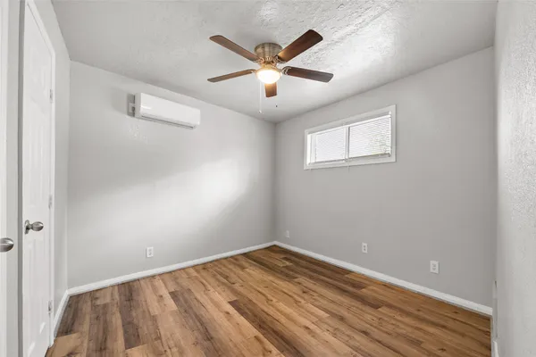 a view of an empty room with wooden floor and a ceiling fan