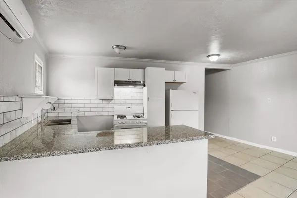 a large kitchen with granite countertop a sink and a refrigerator