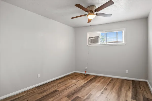 an empty room with a window and a ceiling fan