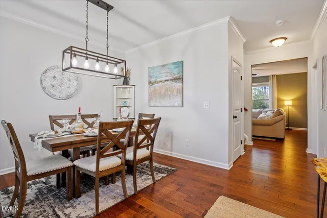 a dining room with wooden floor a chandelier a wooden table and chairs