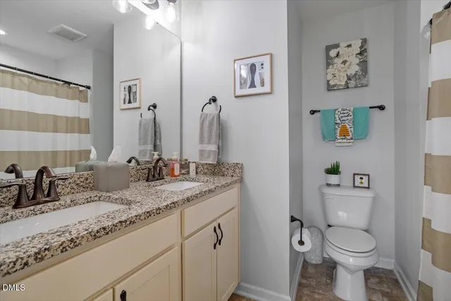 a bathroom with a granite countertop sink toilet and a mirror