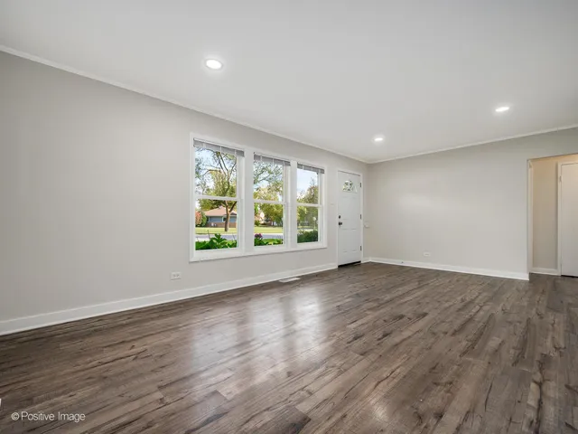 a view of an empty room with wooden floor and window
