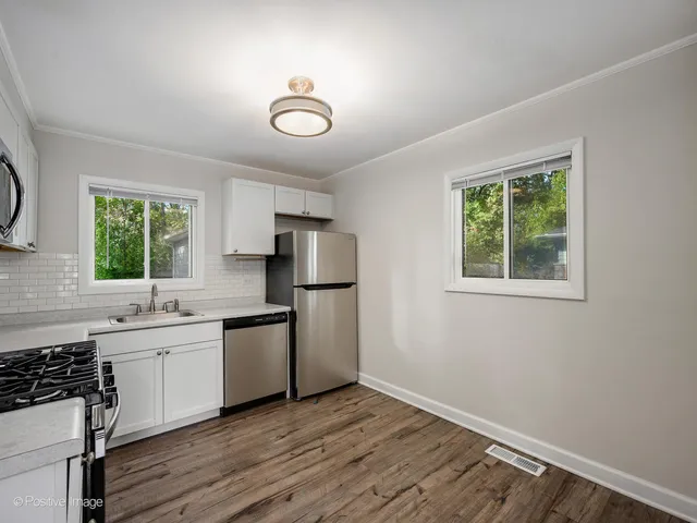a kitchen with a sink appliances cabinets and a window