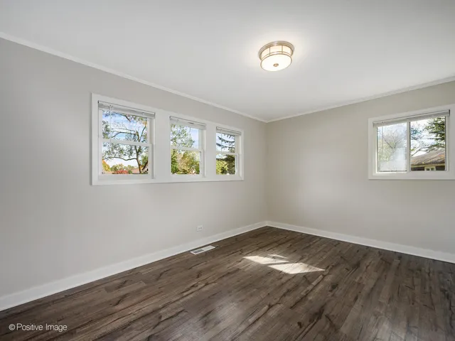 a view of empty room with wooden floor and window