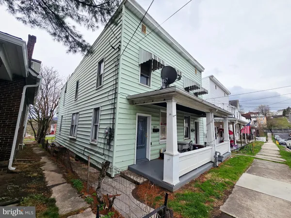 a view of a white house with a small yard and a large tree