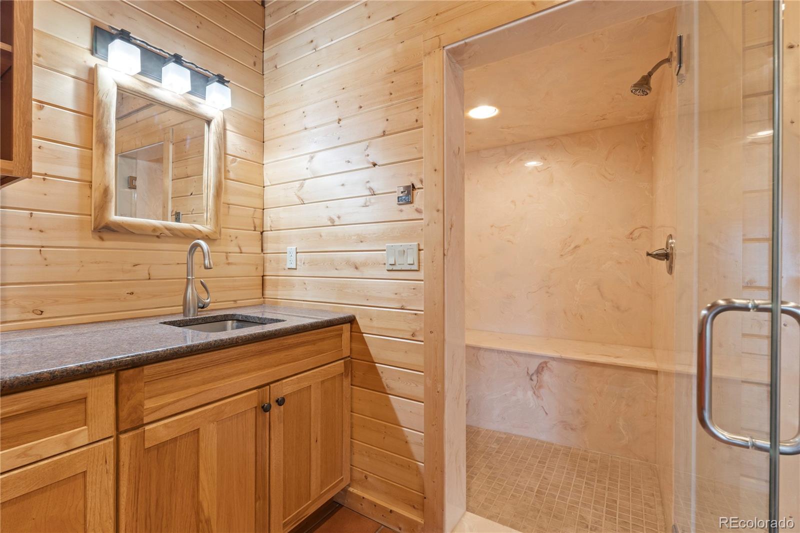 2489 Gross Dam Road Golden, CO 80403 - Photo 32 of 47 a bathroom with a granite countertop sink and a shower