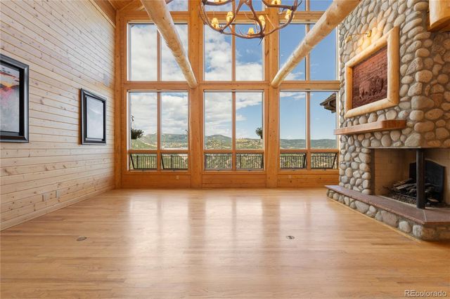 a view of an empty room with wooden floor and a fireplace