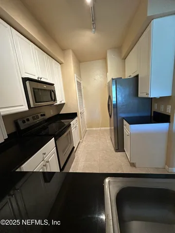 a kitchen with granite countertop white cabinets and appliances