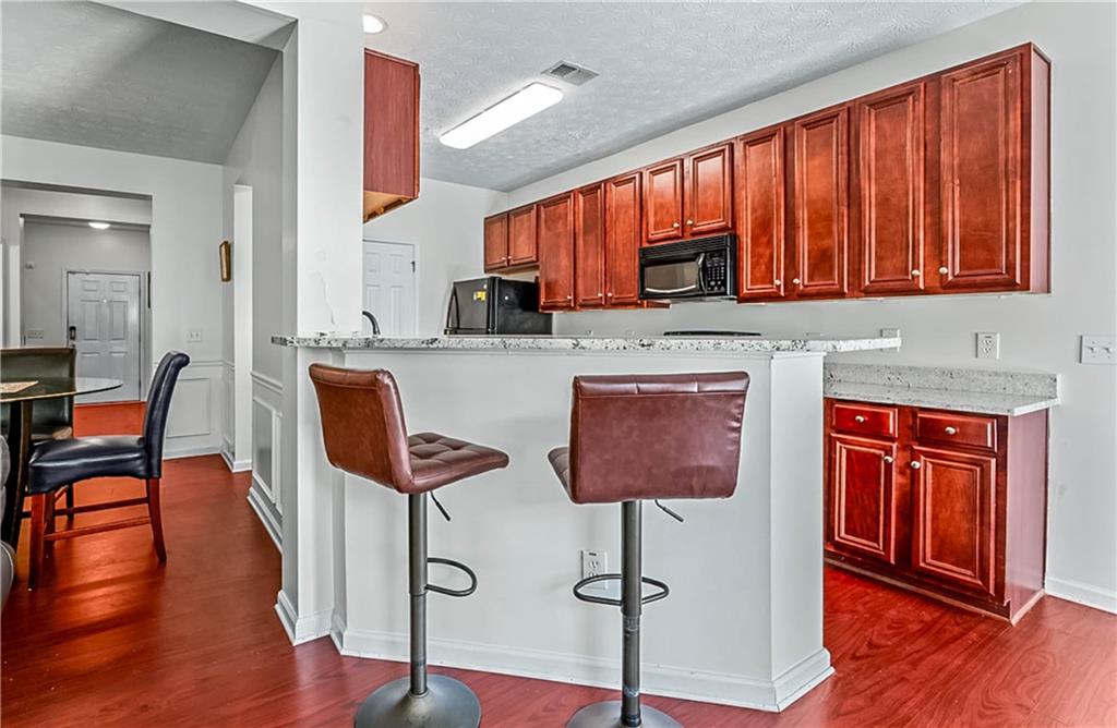 2555 Flat Shoals Road, Unit 2006 Atlanta, GA 30349 - Photo 16 of 29 a kitchen with stainless steel appliances granite countertop a stove top oven a dining table and chairs with wooden floor