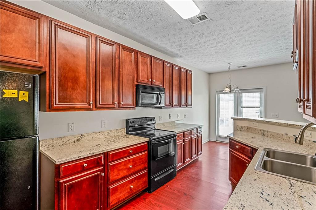2555 Flat Shoals Road, Unit 2006 Atlanta, GA 30349 - Photo 20 of 29 a kitchen with stainless steel appliances granite countertop a stove sink and cabinets