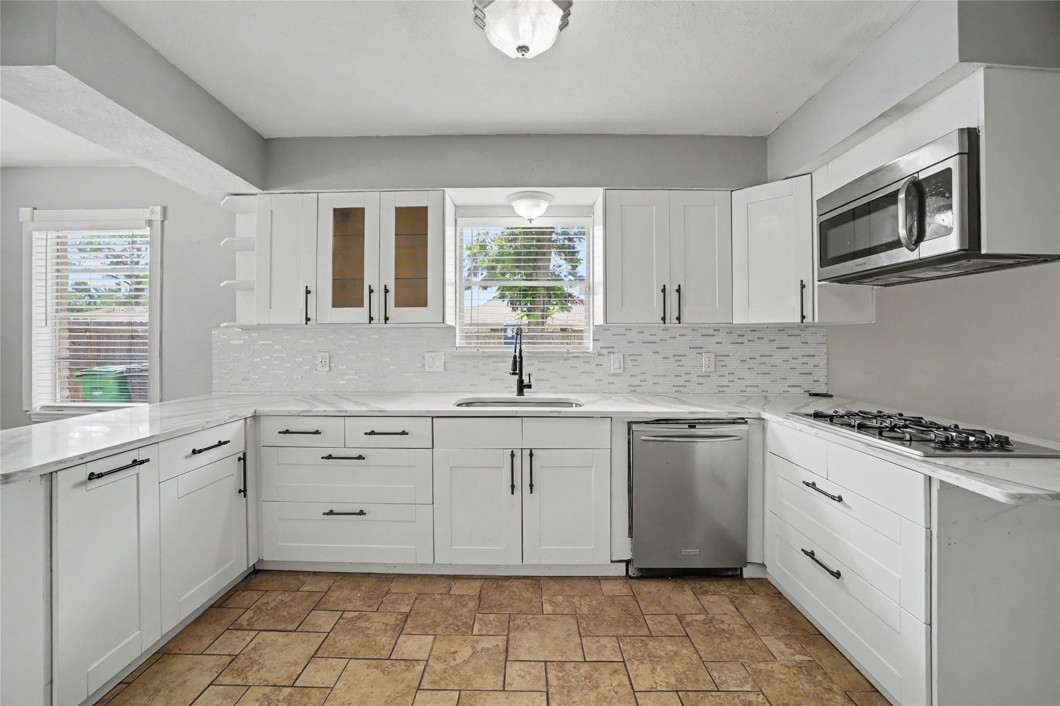 8330 Springtime Lane Houston, TX 77075 - Photo 3 of 27 Modern kitchen featuring sleek white cabinetry, stainless steel appliances, and a striking tile backsplash.