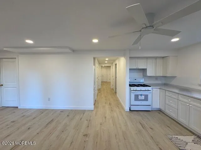 a large kitchen with stainless steel appliances a large counter top a stove a sink dishwasher and a refrigerator with wooden floor