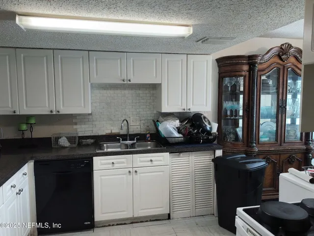a kitchen with granite countertop a sink a stove and cabinets