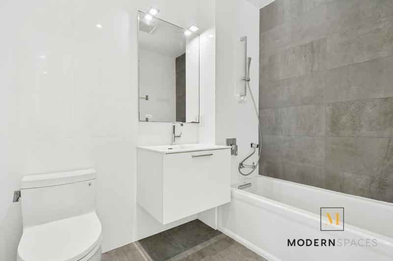 24-12 42nd Road, Unit 4A Queens, NY 11101 - Photo 10 of 17 a bathroom with a toilet a sink a mirror and bathtub