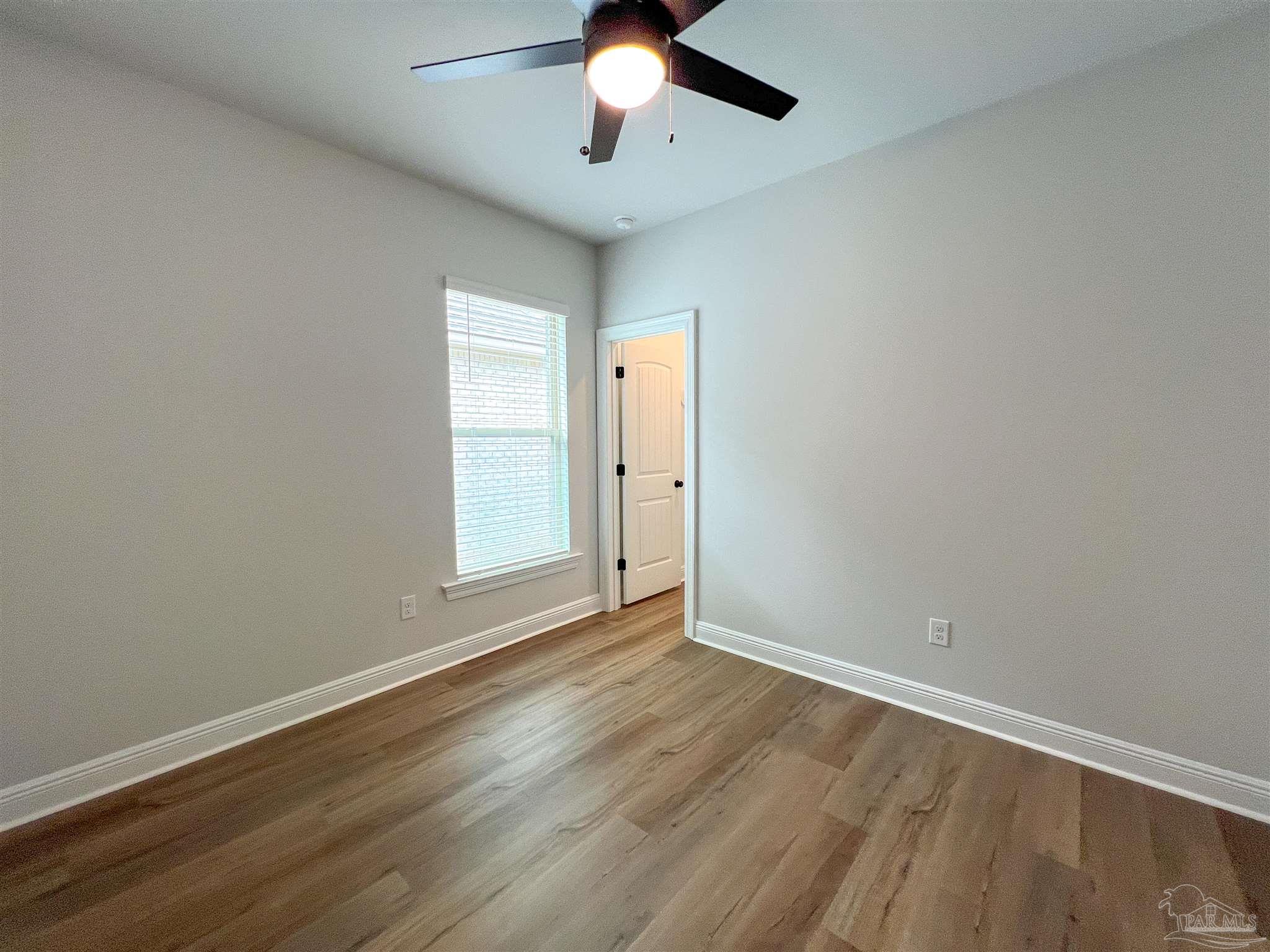 4605 Sago Palm Circle Milton, FL 32571 - Photo 28 of 33 an empty room with wooden floor chandelier fan and windows
