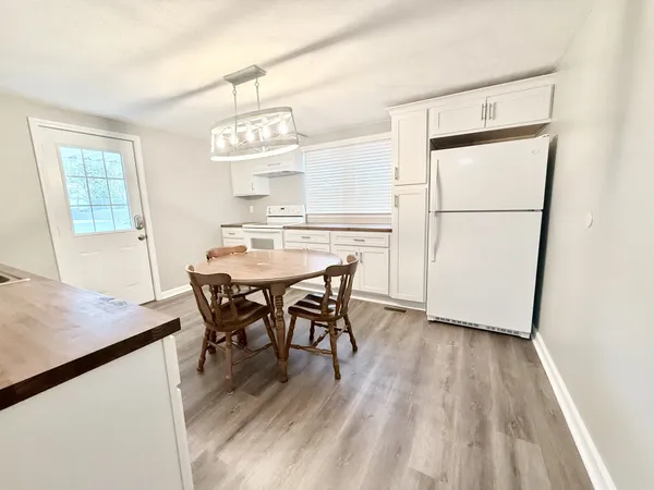 a kitchen with stainless steel appliances a white table chairs and a refrigerator