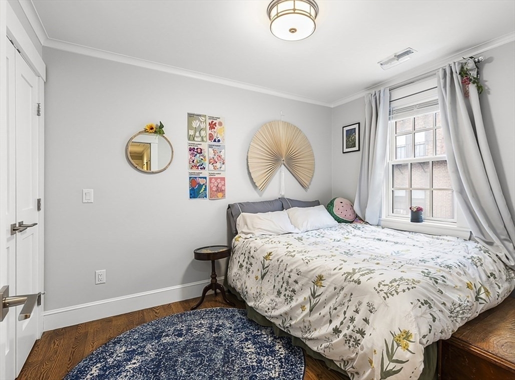 119 Highland Avenue, Unit B Somerville, MA 02143 - Photo 13 of 24 a bed sitting in a bedroom next to a window and a chandelier