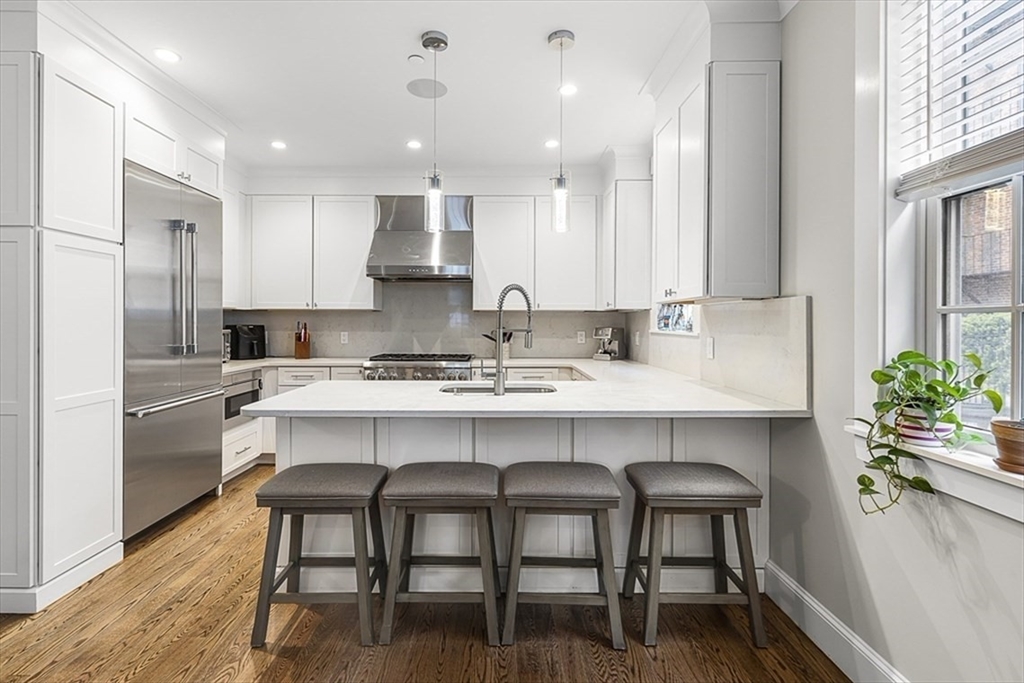 119 Highland Avenue, Unit B Somerville, MA 02143 - Photo 2 of 24 a kitchen with a table chairs refrigerator and microwave