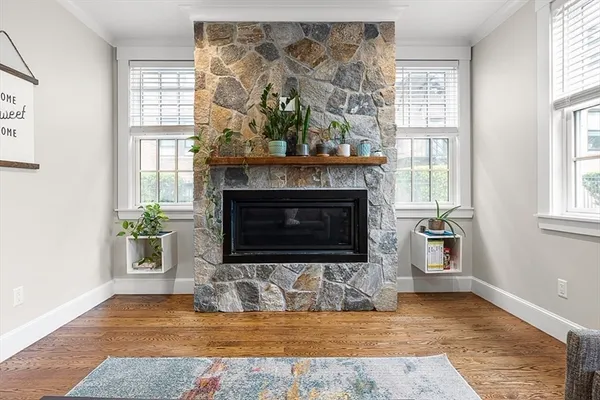 a view of an empty room with wooden floor fireplace and windows