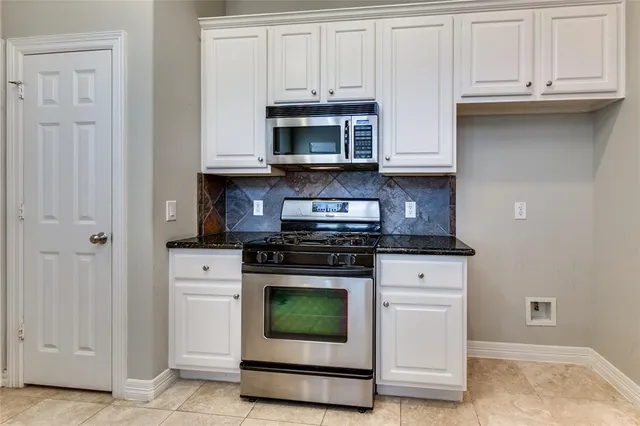 a kitchen with stainless steel appliances granite countertop white cabinets and a stove