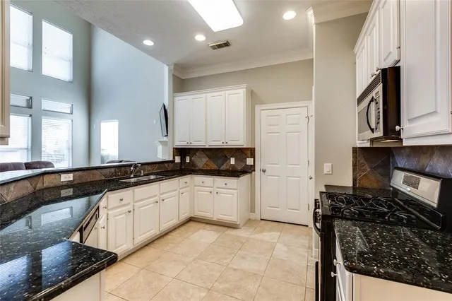 a kitchen with granite countertop a sink stove and cabinets