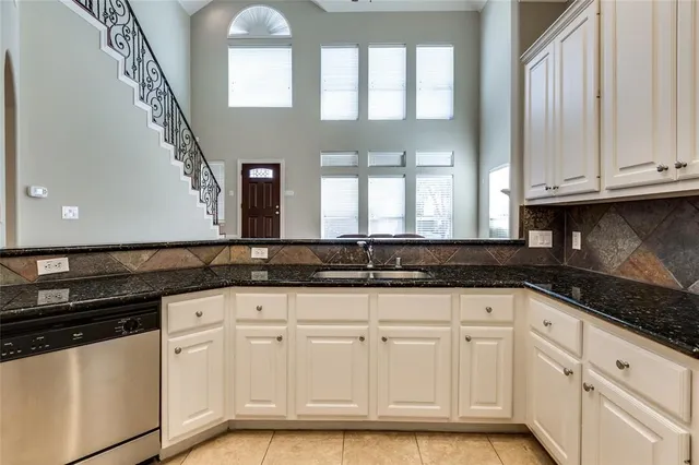 a kitchen with granite countertop white cabinets and sink