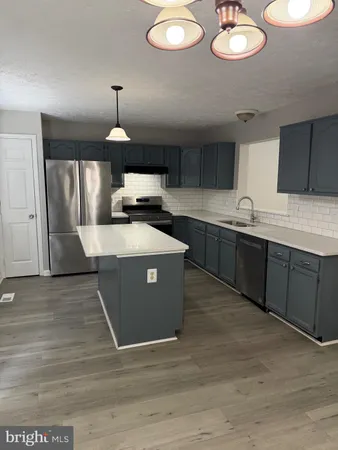 a kitchen with stainless steel appliances granite countertop a sink a stove a refrigerator and island