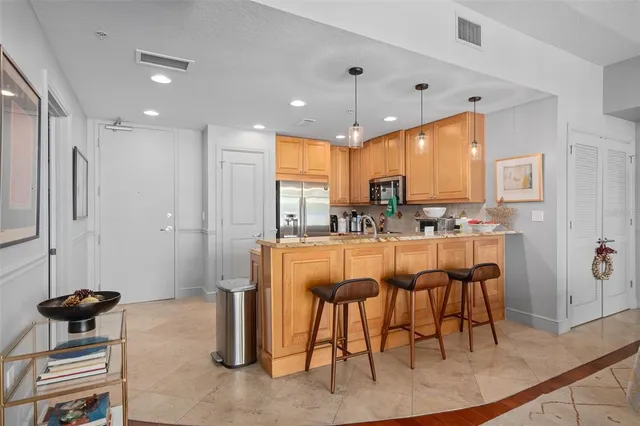 a kitchen with stainless steel appliances granite countertop a sink a stove a refrigerator a dining table and chairs