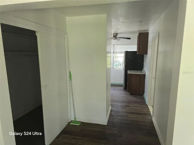 a view of a refrigerator in kitchen and an empty room with wooden floor windows
