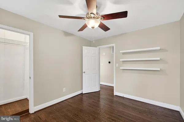 an empty room with wooden floor ceiling fan and windows