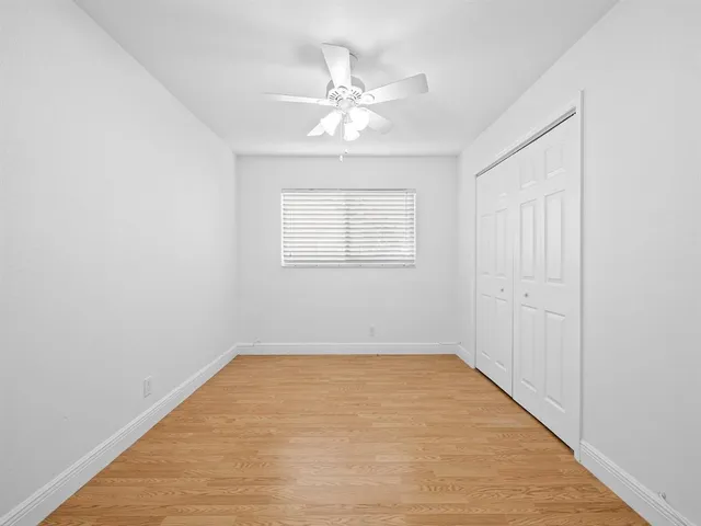 an empty room with a window and a fan