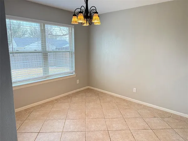an empty room with windows and chandelier fan
