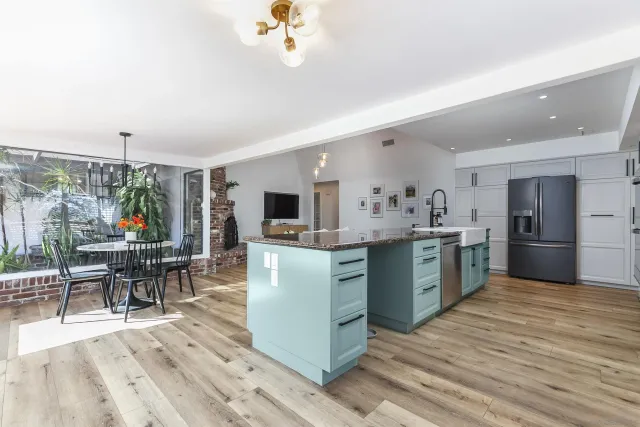 a kitchen with stainless steel appliances kitchen island granite countertop a table chairs sink and cabinets