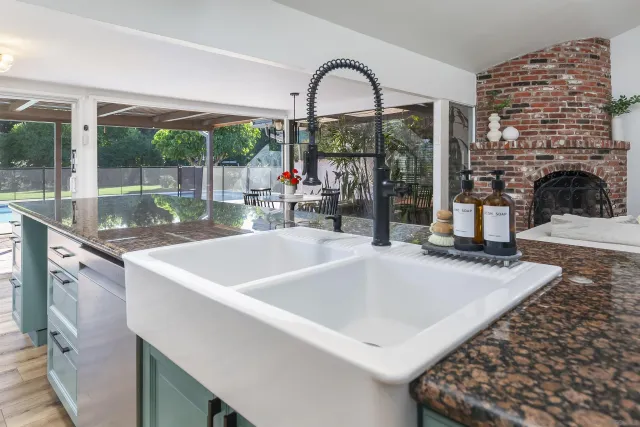 a view of a kitchen with a sink and dishwasher with a fireplace