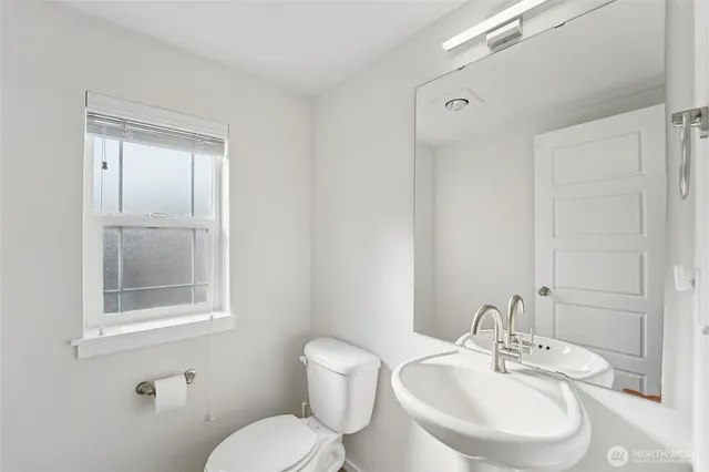 a bathroom with a toilet a sink and mirror