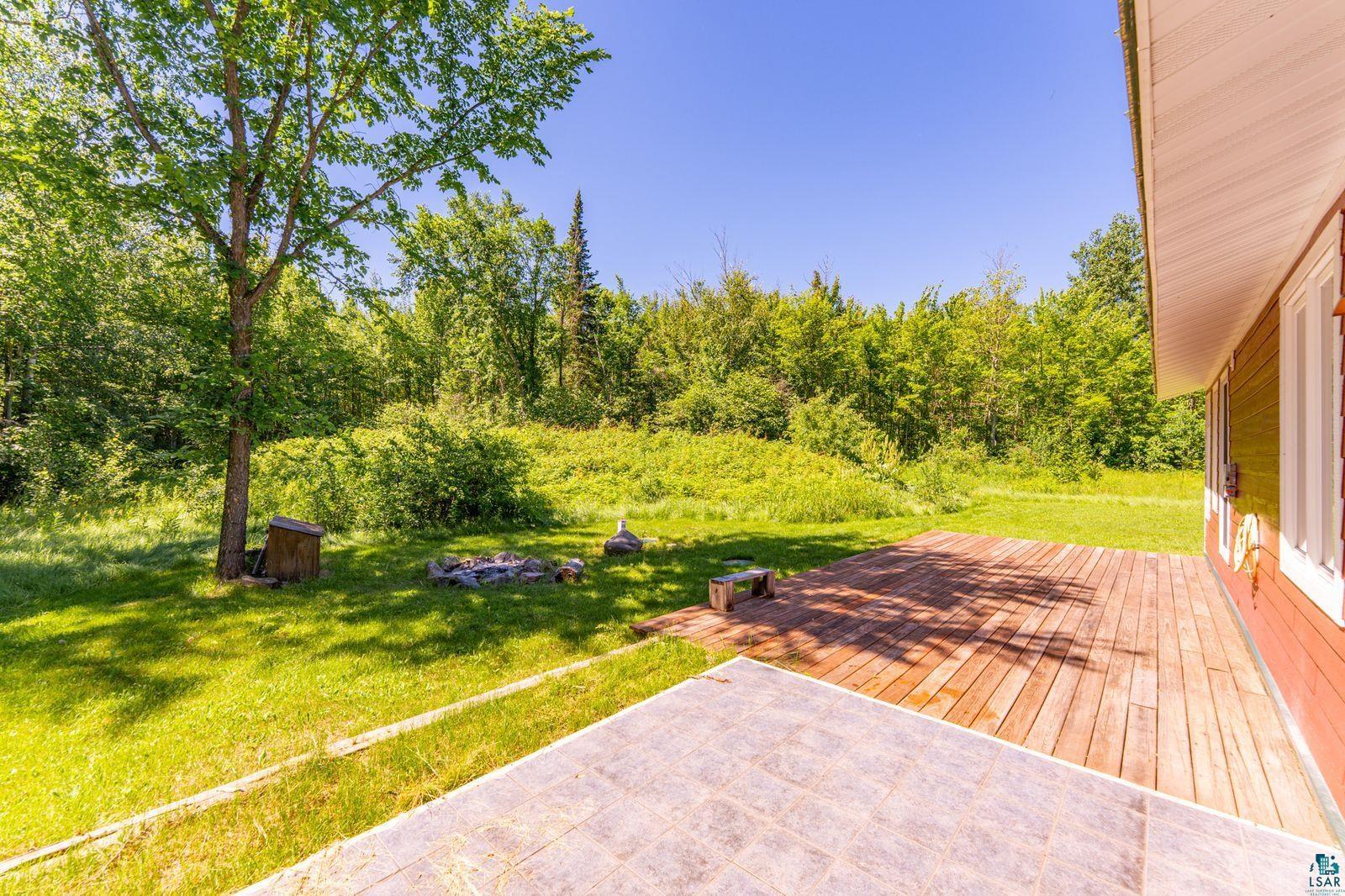 9734 Alango Road Angora, MN 55703 - Photo 27 of 41 Expansive backyard featuring a wood deck, stone patio, and verdant surroundings