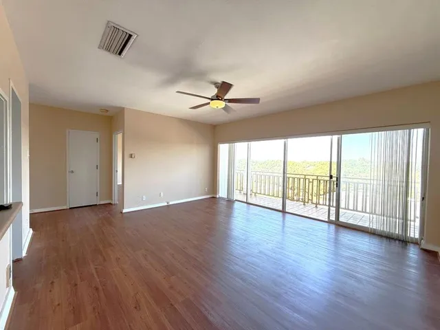 a view of a living room a wooden floor and a ceiling fan